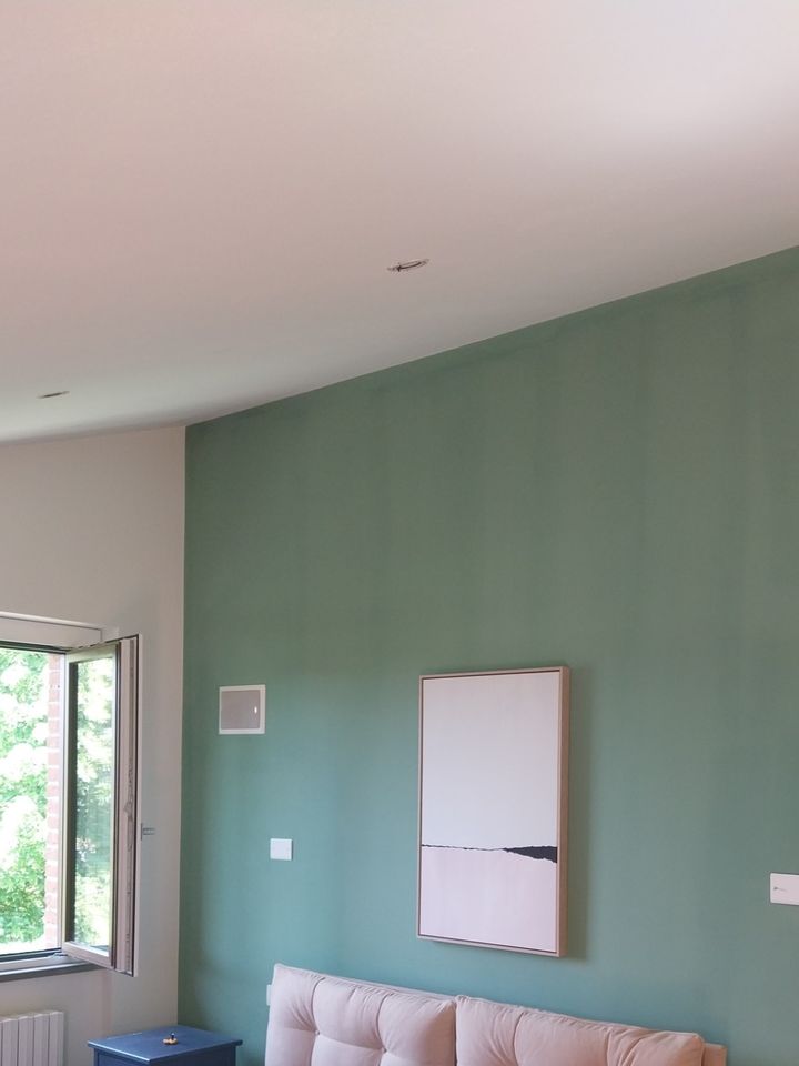Camera da letto con la parete dietro il letto tinteggiata in verde salvia